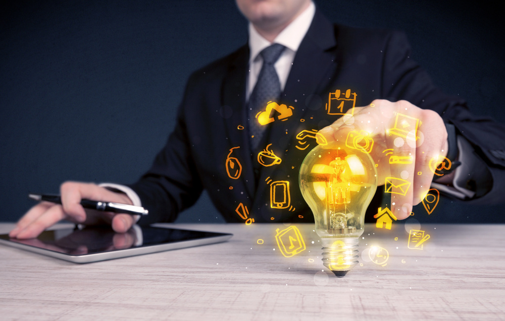 An office salesman promoting his bright ideas concept with illustration of online media and device logos around electric glass light bulb. An office salesman promoting his bright ideas concept with illustration of online media and device logos around electric glass light bulb.